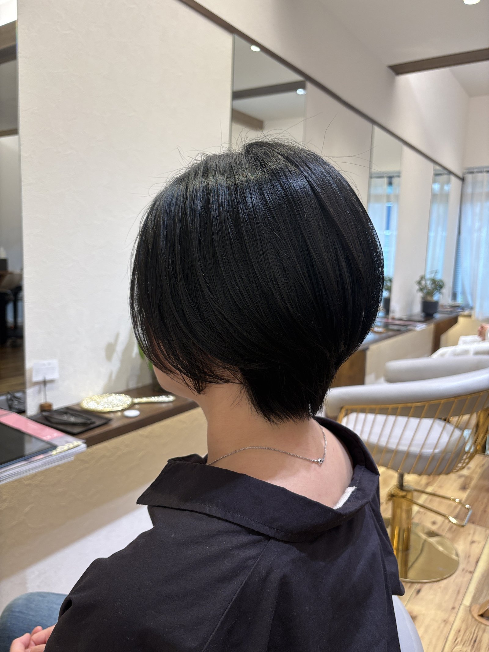 後頭部にふんわりと丸みを持たせたシルエット|襟足はタイトに引き締めた黒髪ショートボブ、斜め後ろ