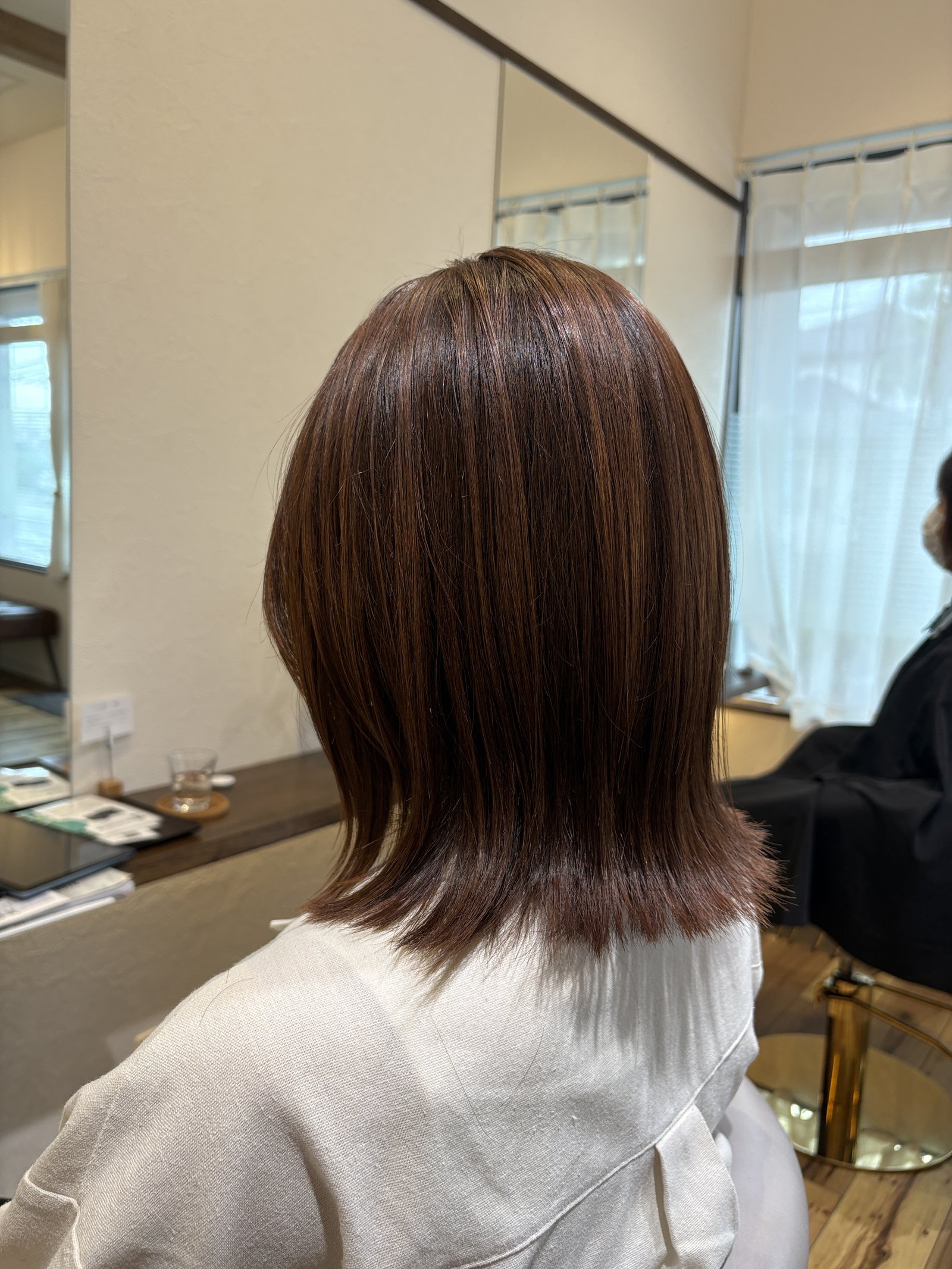 光が当たるとピンクがふわりと立ち上がる質感|肩上ボブの毛先を揃えた後ろ姿、斜め後ろ