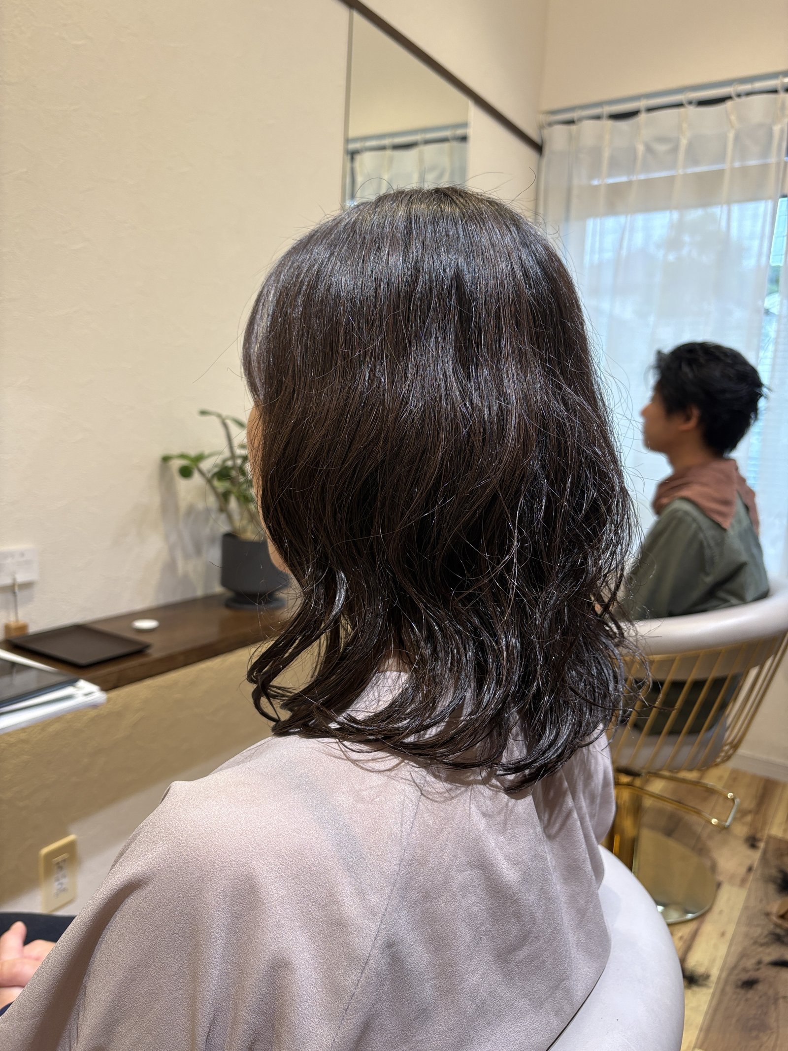 ゆるいウェーブを重ねた暗髪ミディアム｜毛先の動きで軽やかに見せる大人のパーマスタイル、斜め横