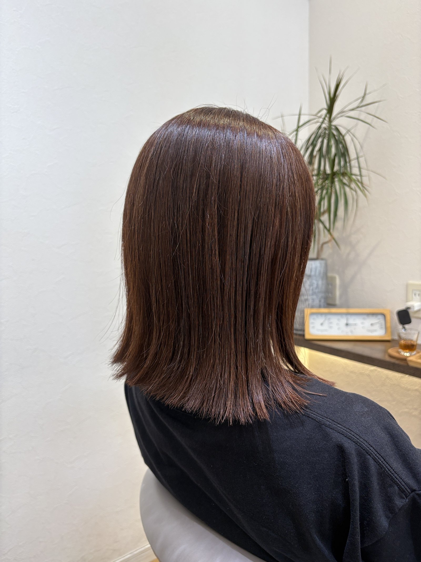 毛先を軽く外ハネにした鎖骨ラインの切りっぱなしミディアム、斜め後ろ