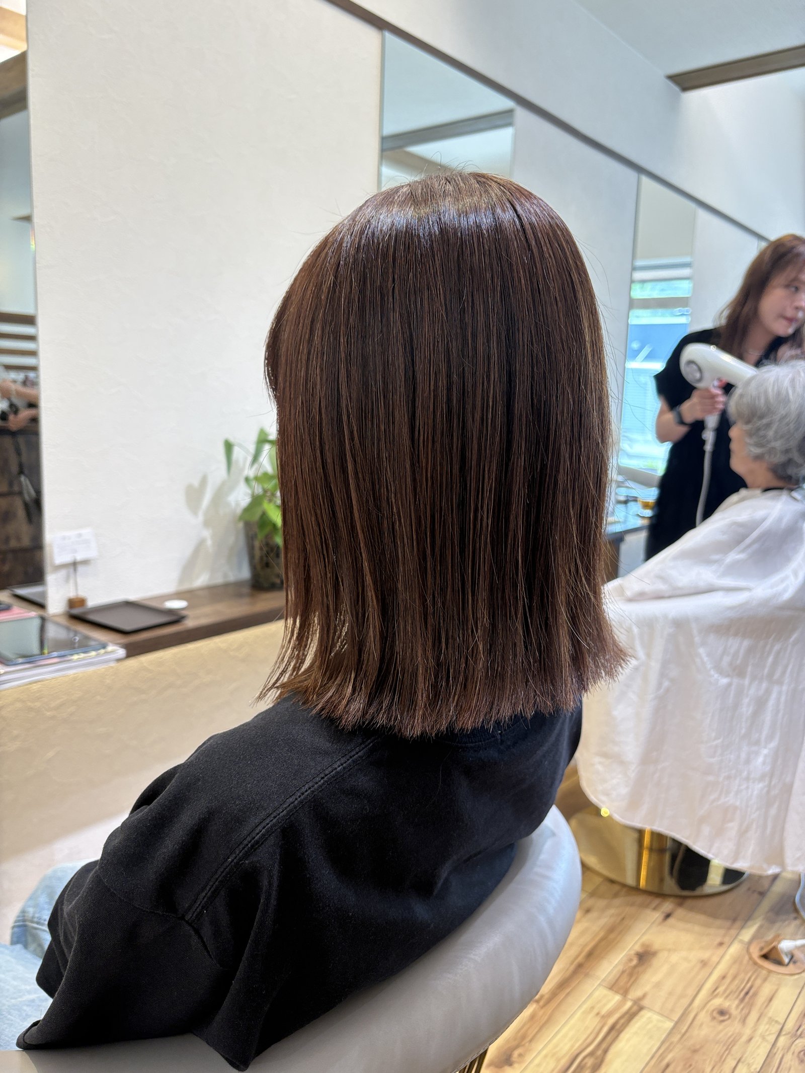 赤みを程よく含んだショコラブラウンのツヤが際立つ切りっぱなしミディアム、斜め横