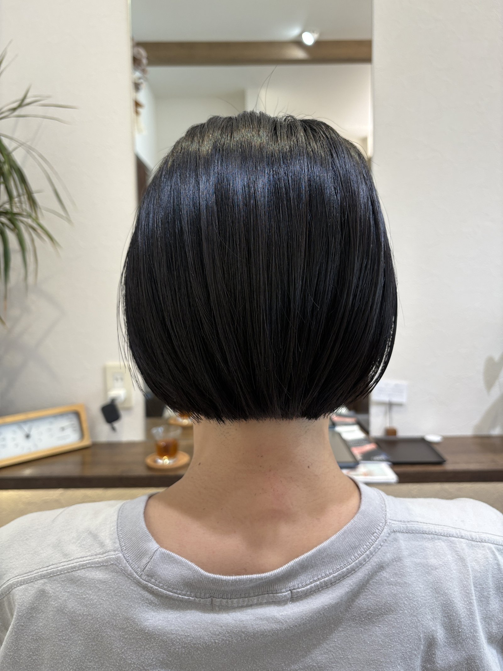 首もとに沿わせてタイトに収めた襟足と、まとまりのある黒髪の後ろ姿、真後ろ