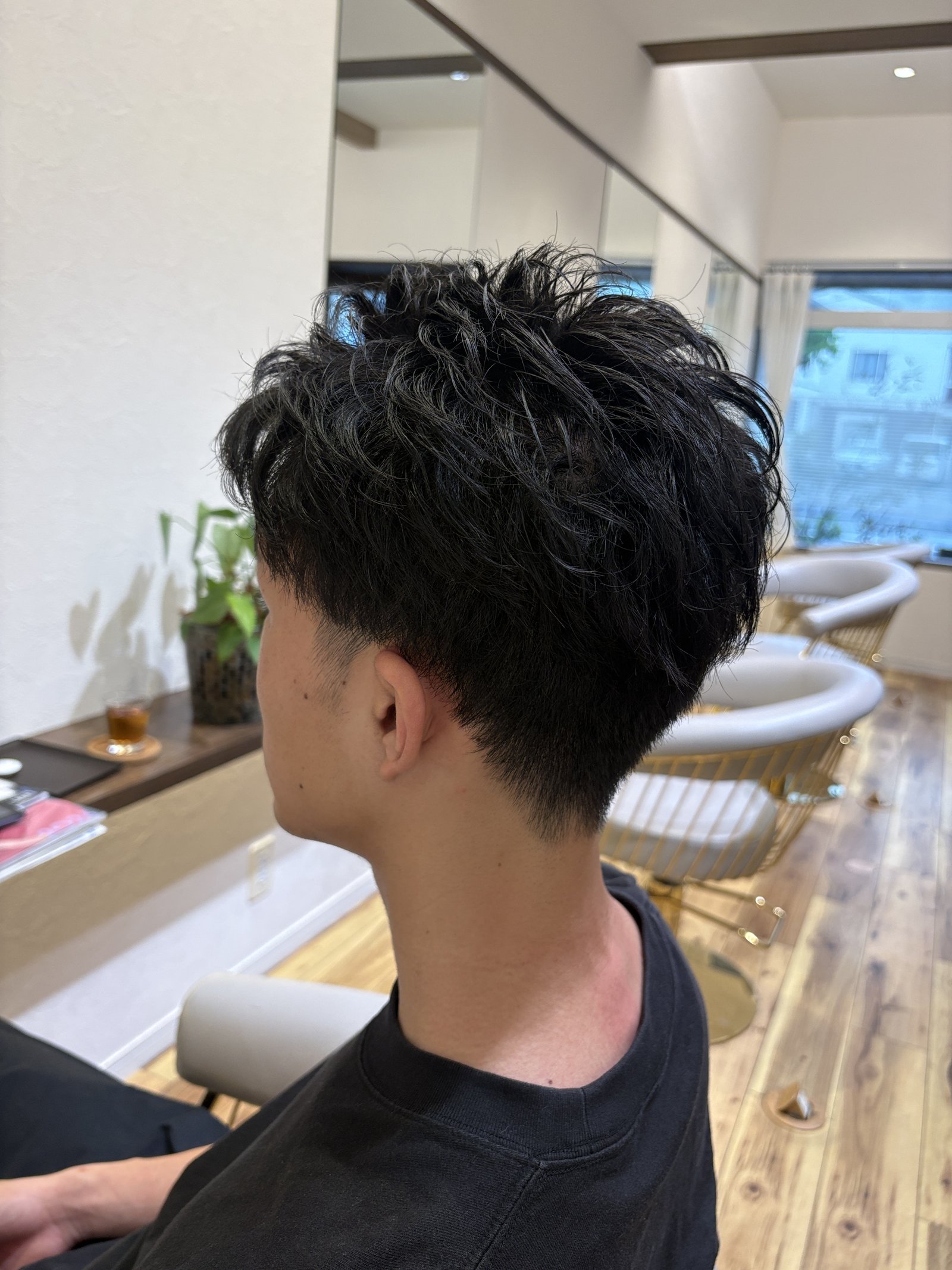 黒髪ニュアンスパーマ×フェードのメンズショート|トップの無造作な毛流れとすっきり刈り上げたサイド、斜め横