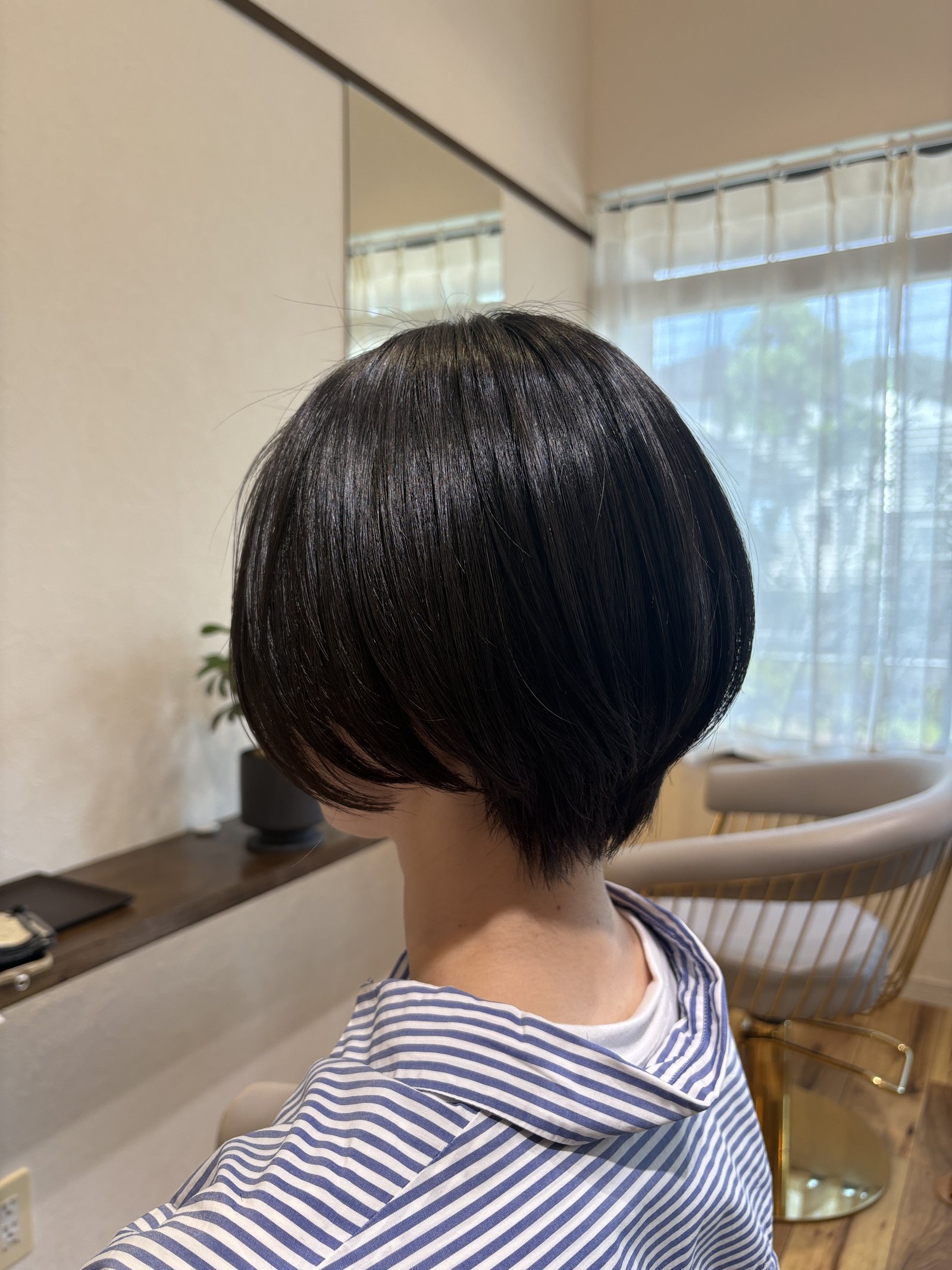 艶やかな黒髪と丸みシルエットが際立つショートボブ|えり足をキュッと締めた大人のコンパクトスタイル、斜め横