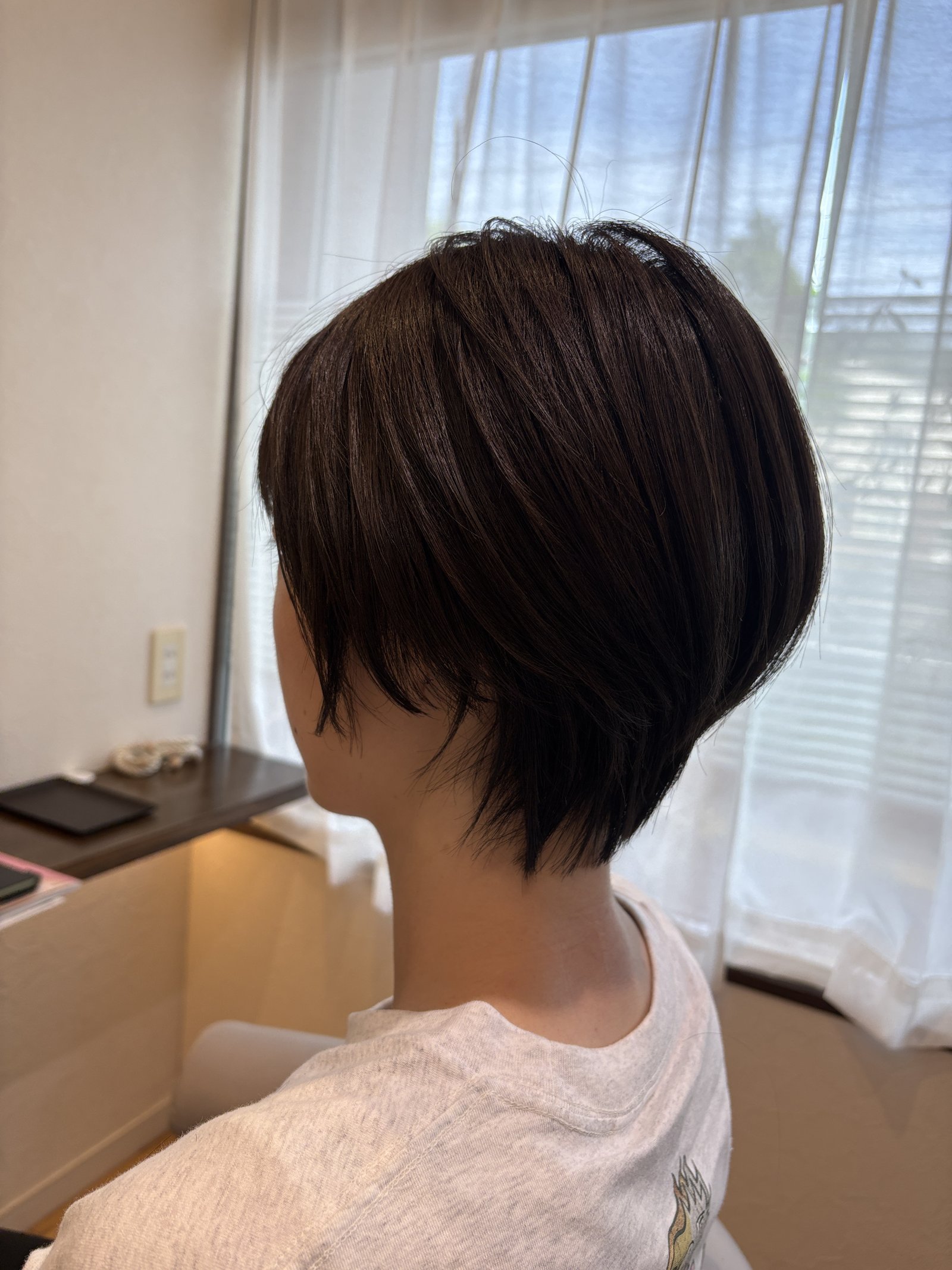 艶やかな暗髪のハンサムショート|後頭部の丸みから襟足へ流れるシャープなライン、斜め横
