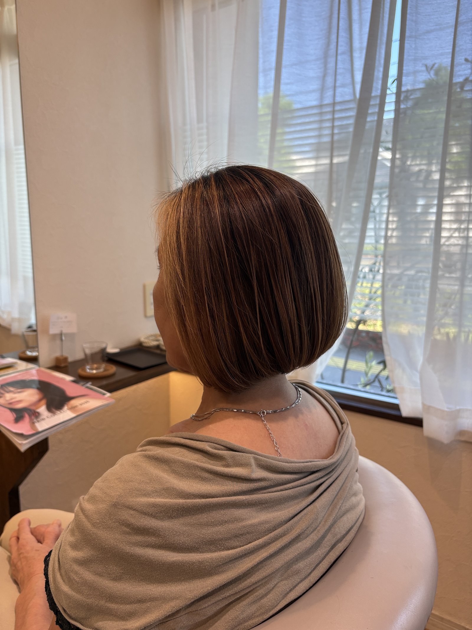 明るめベージュブラウンに細かなハイライト|動くたびに立体感が出る前下がりボブ、斜め後ろ