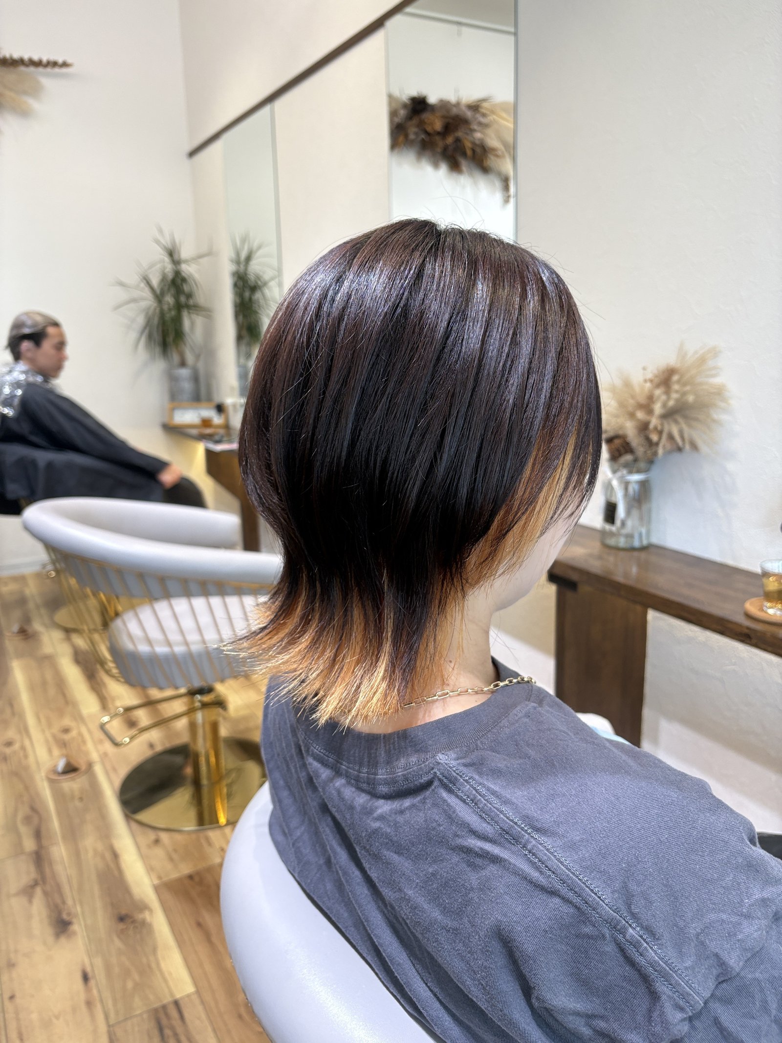 斜め後ろから見たショートウルフ=丸みのレイヤーからくびれて落ちる襟足と、耳の後ろからのぞくブリーチインナー