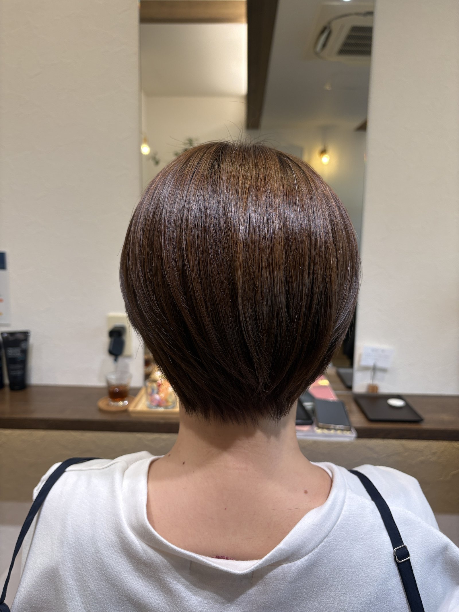 明るめベージュの大人の丸みショート|後頭部の丸みとタイトなえり足のライン、真後ろから