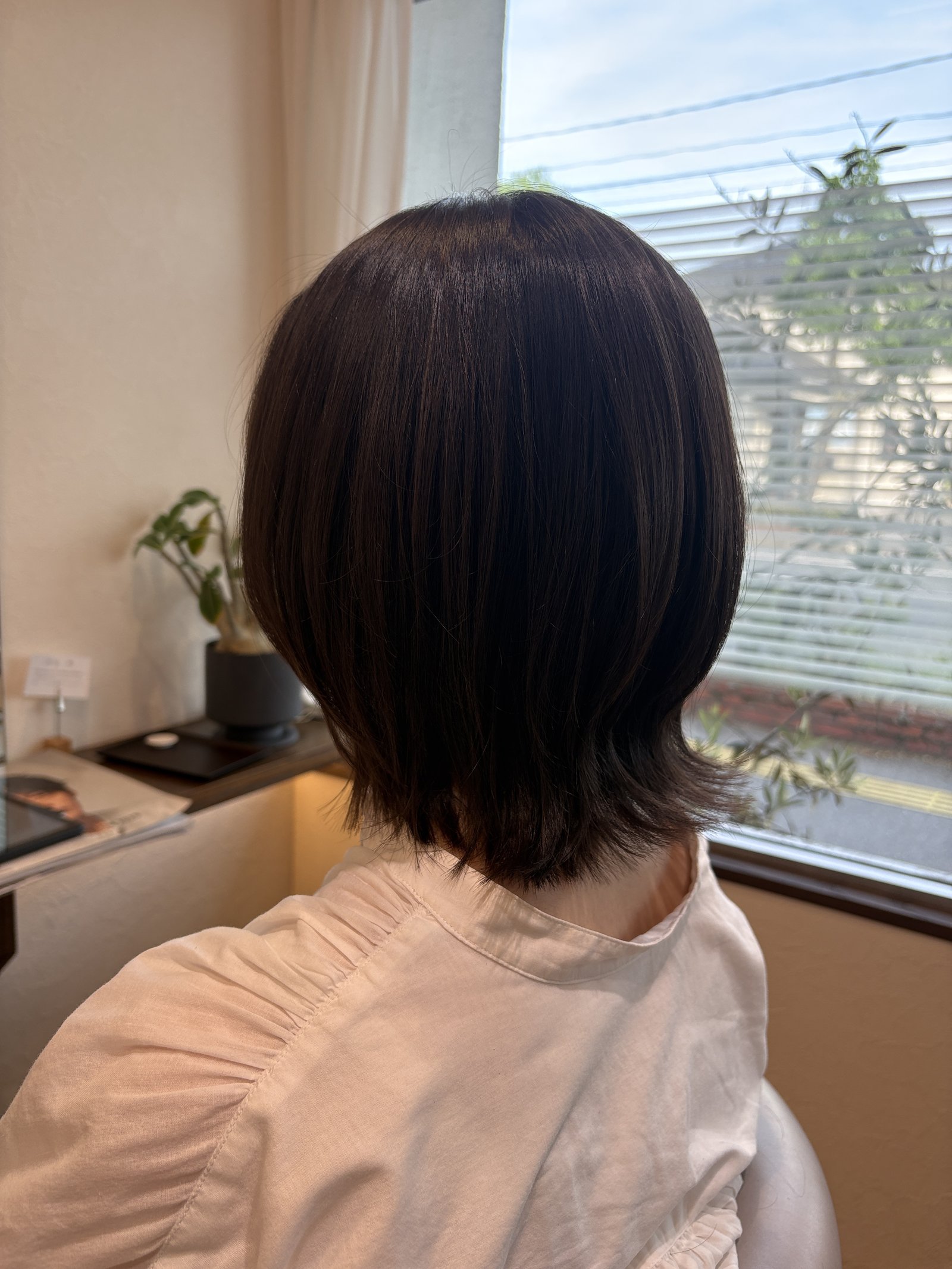 ショコラブラウンのくびれミディアムボブ|表面の丸みから首もとのくびれ、軽く外へ逃がした毛先まで斜め後ろから