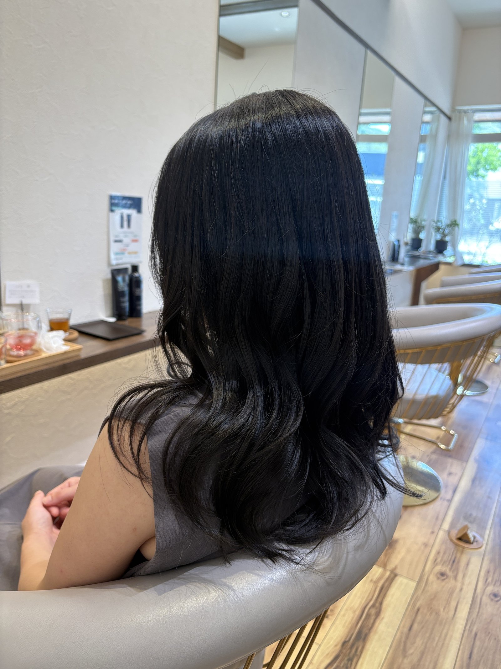 段入りの大人ロング｜毛先の段で、巻いた毛束が少しずつずれて重なり、やわらかく揺れる・左からの斜め後ろ