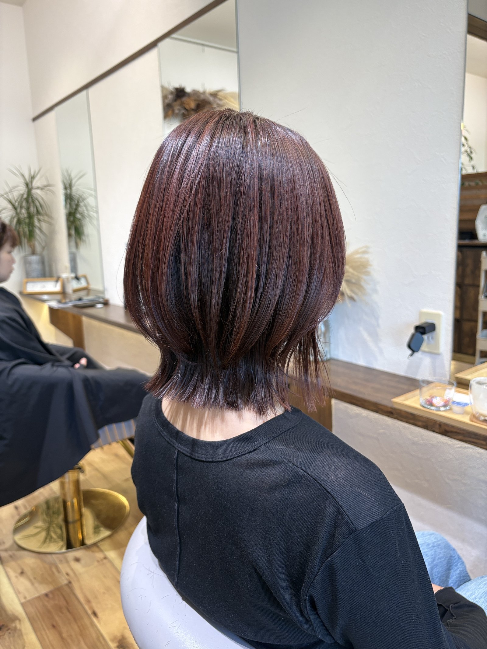 ピンクブラウンのレイヤーくびれボブ|くびれから外ハネへ続く毛先の流れと、ツヤのある表面、左からの斜め後ろ