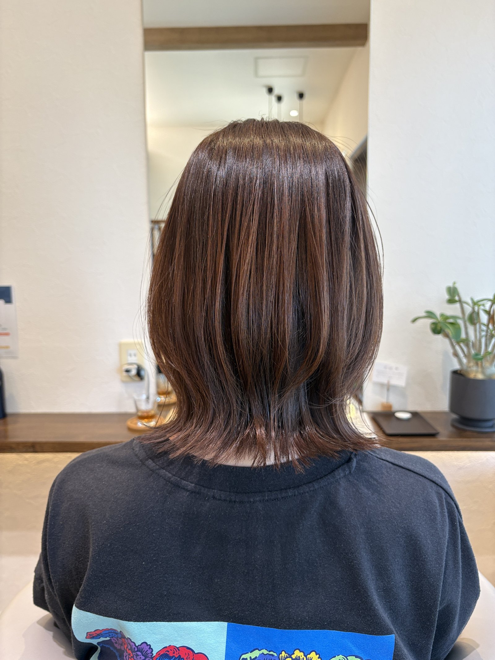 ピンクブラウンベージュのくびれミディアム|表面のなめらかなツヤと、毛先までの段の入り方を後ろから