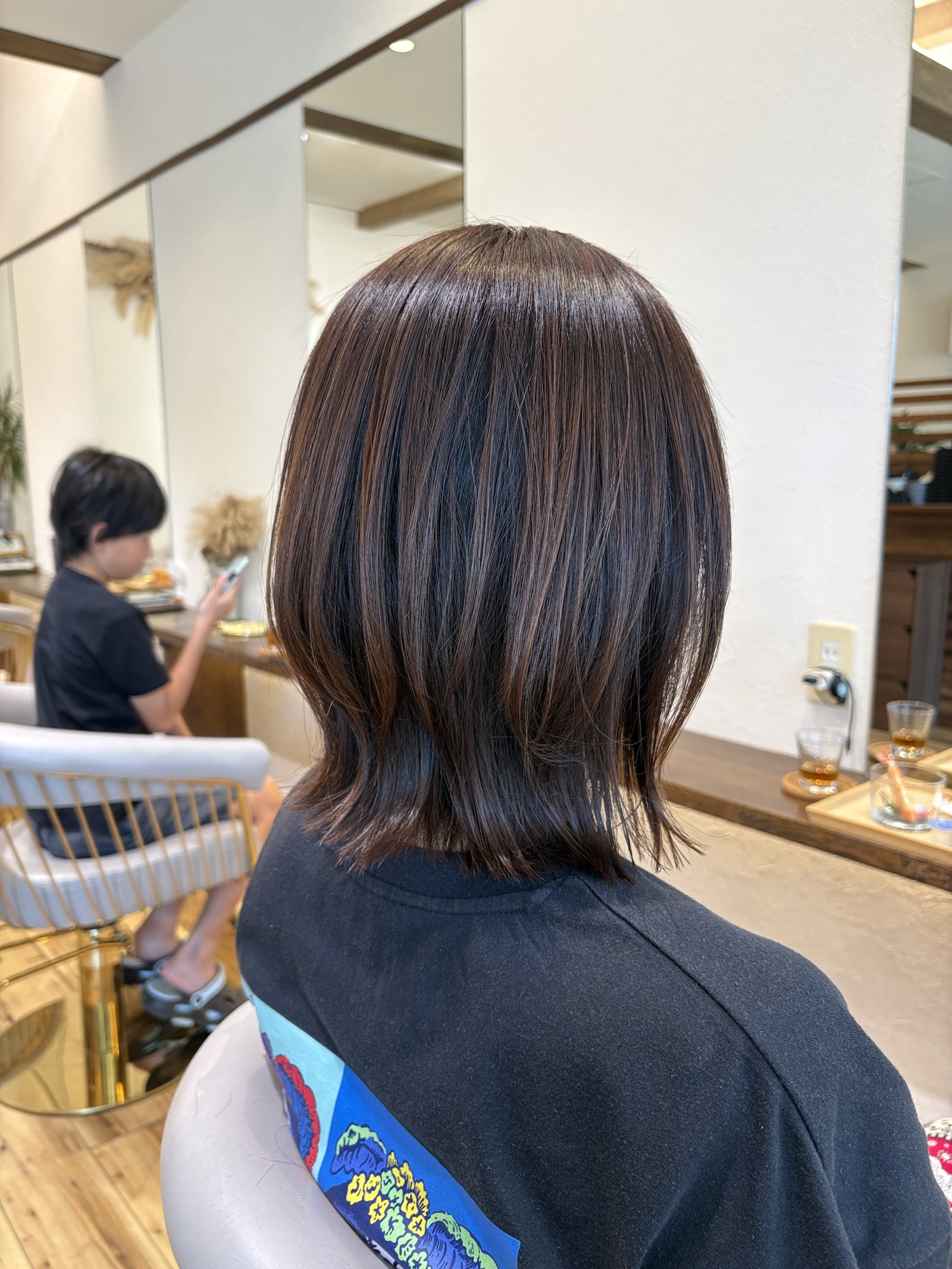 段を入れて首もとを軽くしたくびれミディアム|ピンクブラウンベージュのツヤと毛先の動きを反対側の斜め後ろから