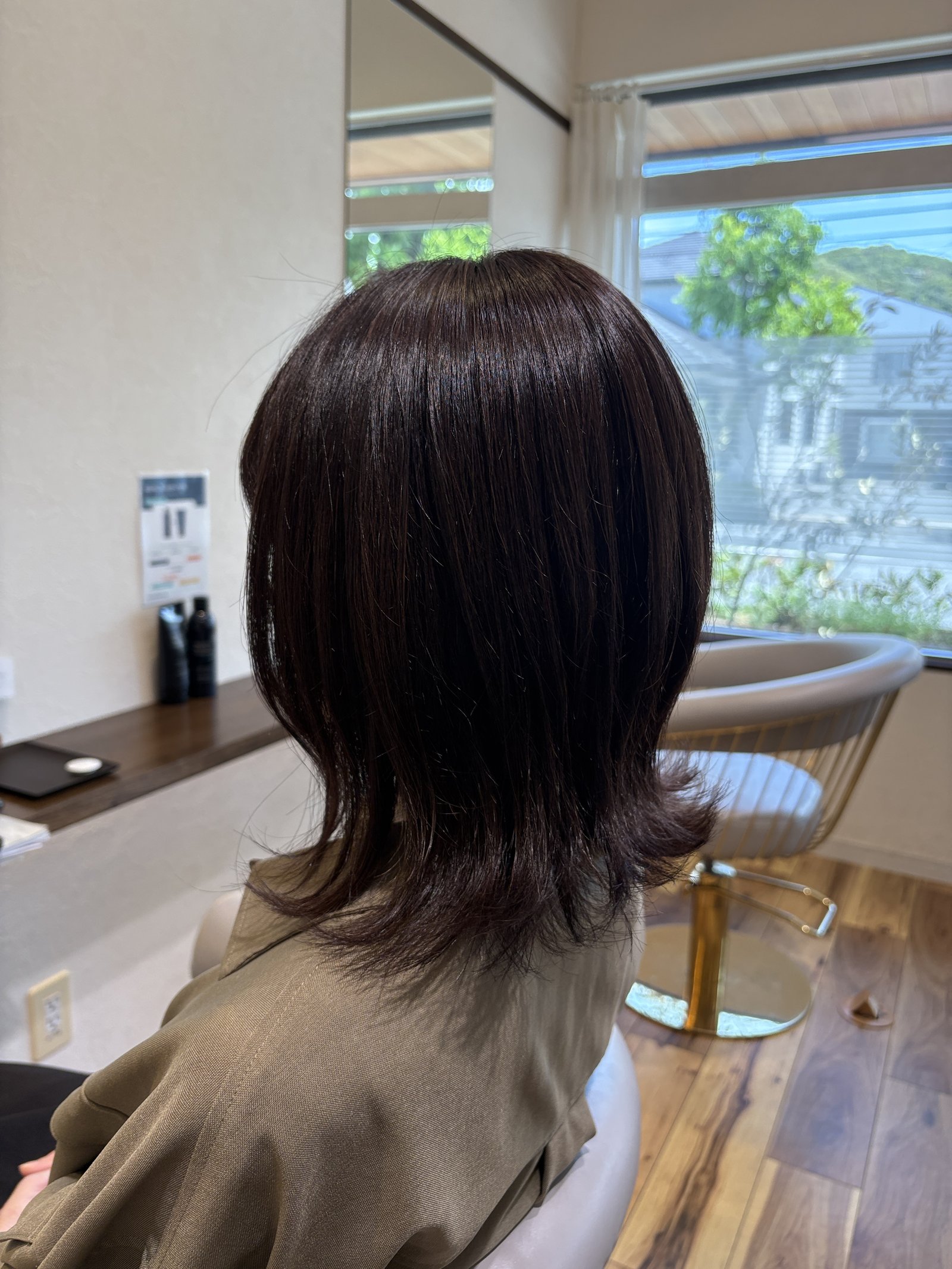 ピンクブラウンの外ハネミディアム|毛先の段がそろって外へ向き、表面はまっすぐなツヤ・右からの斜め後ろ